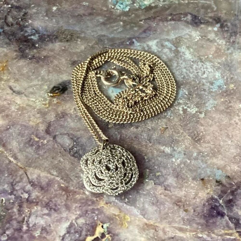silver pendant necklace with intricate floral design and long chain
